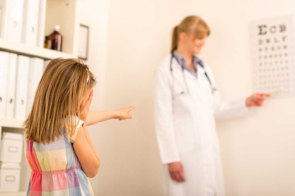 Girl reading eye chart pediatrician office